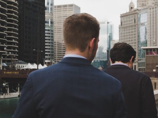 man wearing blue blazer standing behind two men during daaytime