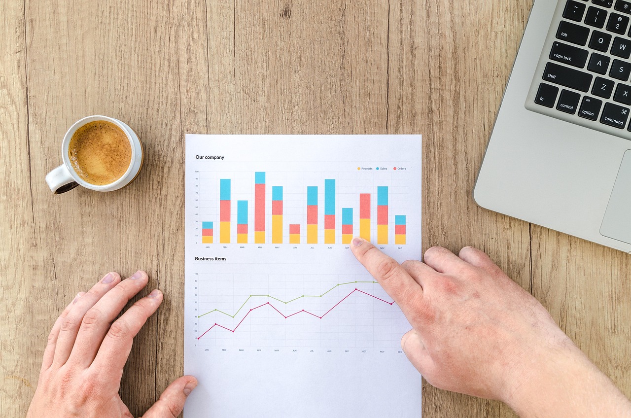 Persoon die maandelijks beleggingen vergelijkt op laptop met spreadsheet en grafiek