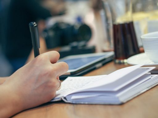 Persoon luistert naar podcast en maakt aantekeningen in notitieboek
